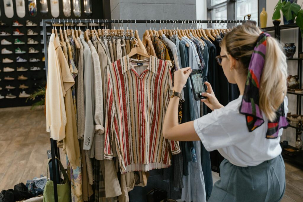 A woman takes photos of stylish clothing in a fashionable boutique, emphasizing trendy fashion.